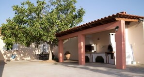 A covered outdoor area with a table, chairs, and a large tree. - Country House 'Evoia Village House' with Mountain View, Wi-Fi and Air Conditioning (Neochori)