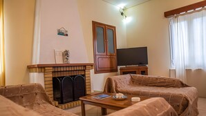 Ein Wohnzimmer mit Kamin, Fernseher und zwei abgedeckten Sofas.