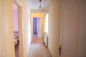 A narrow hallway with a bed and radiator on the left, a door on the right, and a ceiling light. - Country House 'Evoia Village House' with Mountain View, Wi-Fi and Air Conditioning (Neochori)
