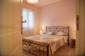 A bedroom with a bed, a bedside table, a lamp, and a window with curtains. - Country House 'Evoia Village House' with Mountain View, Wi-Fi and Air Conditioning (Neochori)
