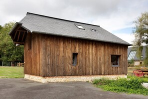 A wooden building with a sloped roof, two windows, and a small porch area. - La Petite Maison de Rose – In the Heart of the Forest (Flancourt-Crescy-en-Roumois)