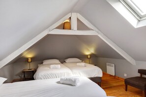 Une chambre avec deux lits, une lucarne et un radiateur.