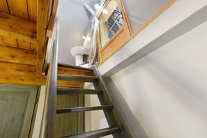 Una escalera de madera que conduce a un baño con inodoro y zona de ducha.
