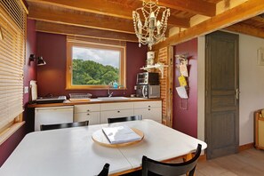 Une cuisine de taille réduite avec une fenêtre, un lustre et une table à manger avec des chaises.