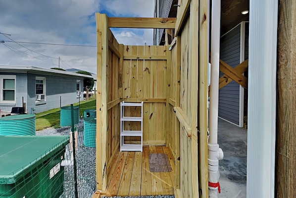 A wooden structure with a ladder, a white shelf, and a small mat on the floor.