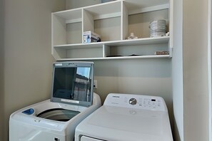 A laundry area with two washing machines and shelves above.