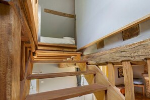 Un escalier en bois à plusieurs niveaux, avec un lit superposé en haut.