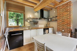 Une cuisine avec un mur en briques, des poutres en bois, une fenêtre et un lave-vaisselle de la marque Bosch.