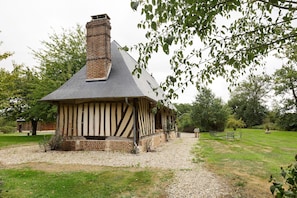 Une maison traditionnelle à ossature en bois, dotée d’un toit à forte pente et d’une cheminée en briques.