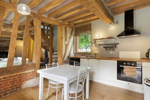 A kitchen with a wooden ceiling, white cabinets, and a Bosch oven.