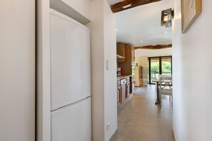 A kitchen with wooden cabinets, a white refrigerator, and a dining area with a table and chairs.