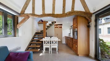 A modern interior with exposed wooden beams, a staircase, a dining area, and a kitchen.