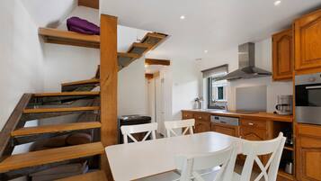 Una cocina moderna con armarios de madera, una mesa de comedor con sillas y una escalera con un cojín morado.