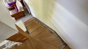 A room with a wooden floor, a white wall, and a wooden chair with a cushion. - The Cottage – In the Heart of a 20-Hectare Estate (Flancourt-Crescy-en-Roumois)
