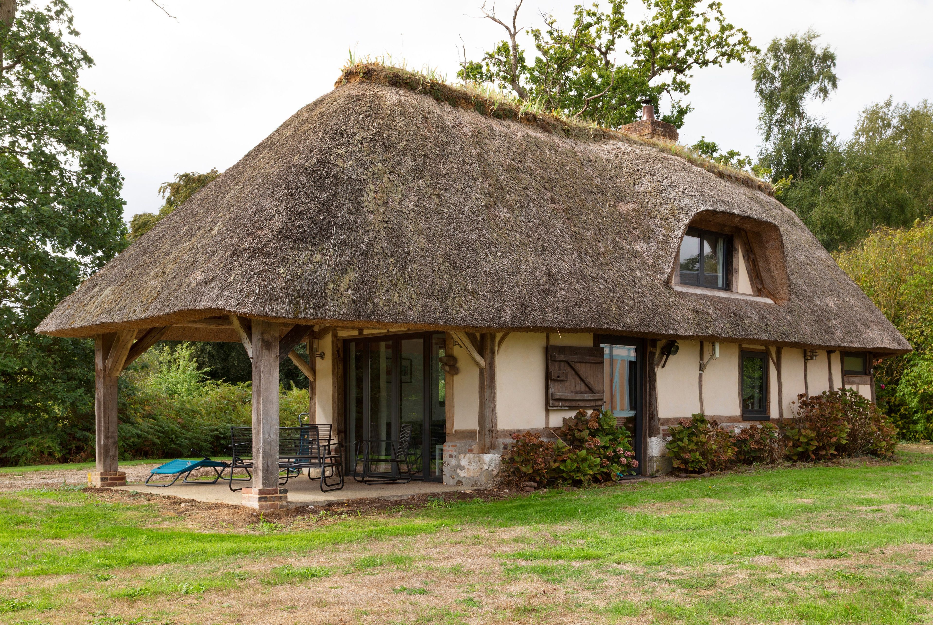 Una casa con techo de paja y un porche cubierto, con un ventanal pequeño.