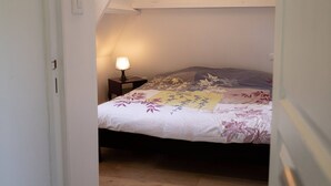 A bedroom with a bed, a nightstand, and a lamp. - The Cottage – In the Heart of a 20-Hectare Estate (Flancourt-Crescy-en-Roumois)