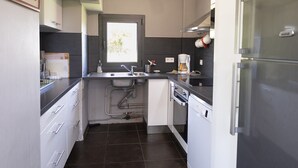 Een kleine keuken met een spoelbak, een koffiezetapparaat en een vaatwasser.
