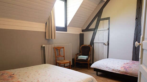 Een slaapkamer met twee bedden, een stoel, een radiator en een raam.