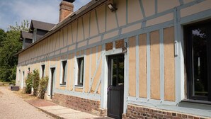 Een gebouw met een traditionele vakwerkmurengevel, meerdere ramen en een bakstenen fundering.