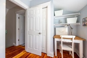 A room with a wooden floor, white door, white desk with a chair, and white shelving with decorative items. - Dharma Cottage - A Quiet 3BR Coastal Getaway in Historic Fairhaven (Fairhaven)