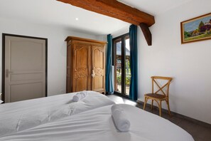 Ein Schlafzimmer mit einem Bett, einem Holzschrank, einem Stuhl und einem Gemälde an der Wand.