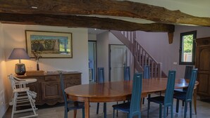 Ein Essbereich mit Holztisch und Stühlen, einer Treppe und einem Bild an der Wand.