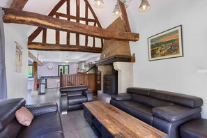 Ein modernes Wohnzimmer mit Kamin, Ledersofas und freiliegenden Holzbalken.