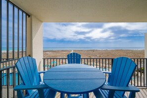 A balcony with a table and chairs, overlooking a beach and ocean. - Phoenix Vii 7207 1 Bedroom Condo (Orange Beach)