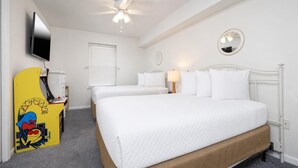 Ein Hotelzimmer mit einem Bett, einem Fernseher, einem Deckenventilator, einem Fenster mit Jalousien und einer Nachttischlampe.