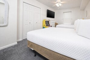 A hotel room with a bed, a television, a ceiling fan, and a door. - Phoenix Vii 7501 3 Bedroom Condo (Orange Beach)
