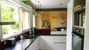 Cozinha moderna com parede de pedra, forno embutido e área de refeições com sofá.