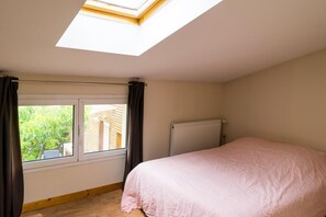 Et soveværelse med ovenlys, en radiator og udsigt til grøn vegetation.