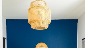 Um quarto com uma cama, um espelho redondo, um abajur de vime e uma cadeira.