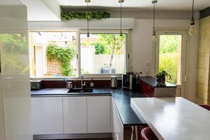 Et moderne køkken med et stort vindue, en vask og en bordplade med diverse hårde hvidevarer.