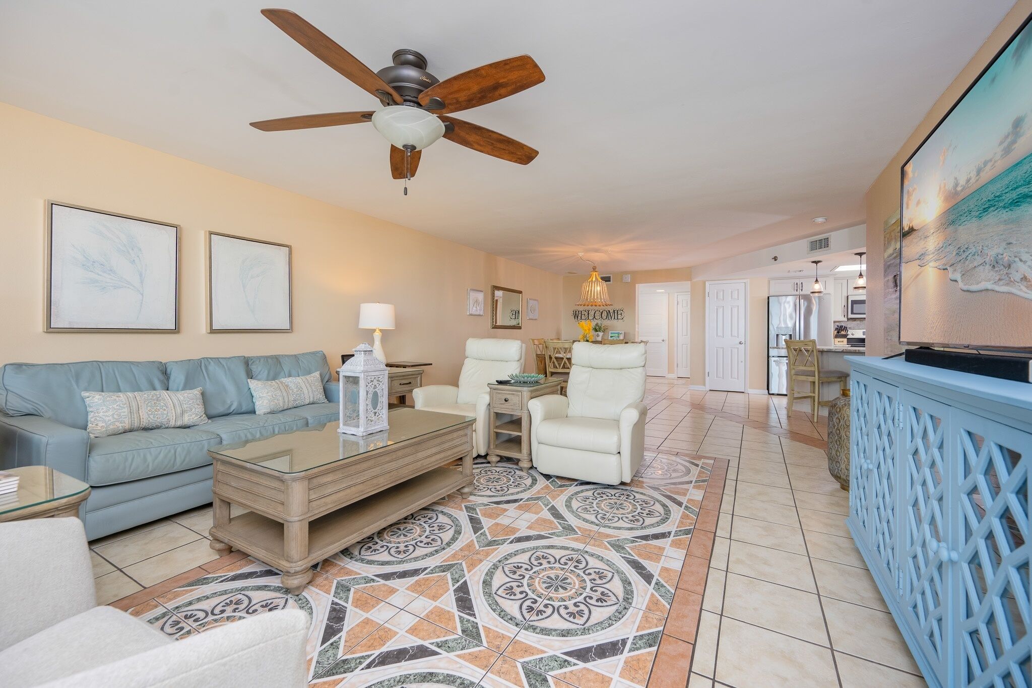 A spacious living room with a ceiling fan, a sofa, a coffee table, and a patterned rug.