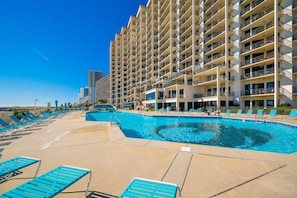 A hotel with a swimming pool, multiple balconies, and a clear blue sky. - Phoenix Vii 7208 3 Bedroom Condo (Orange Beach)