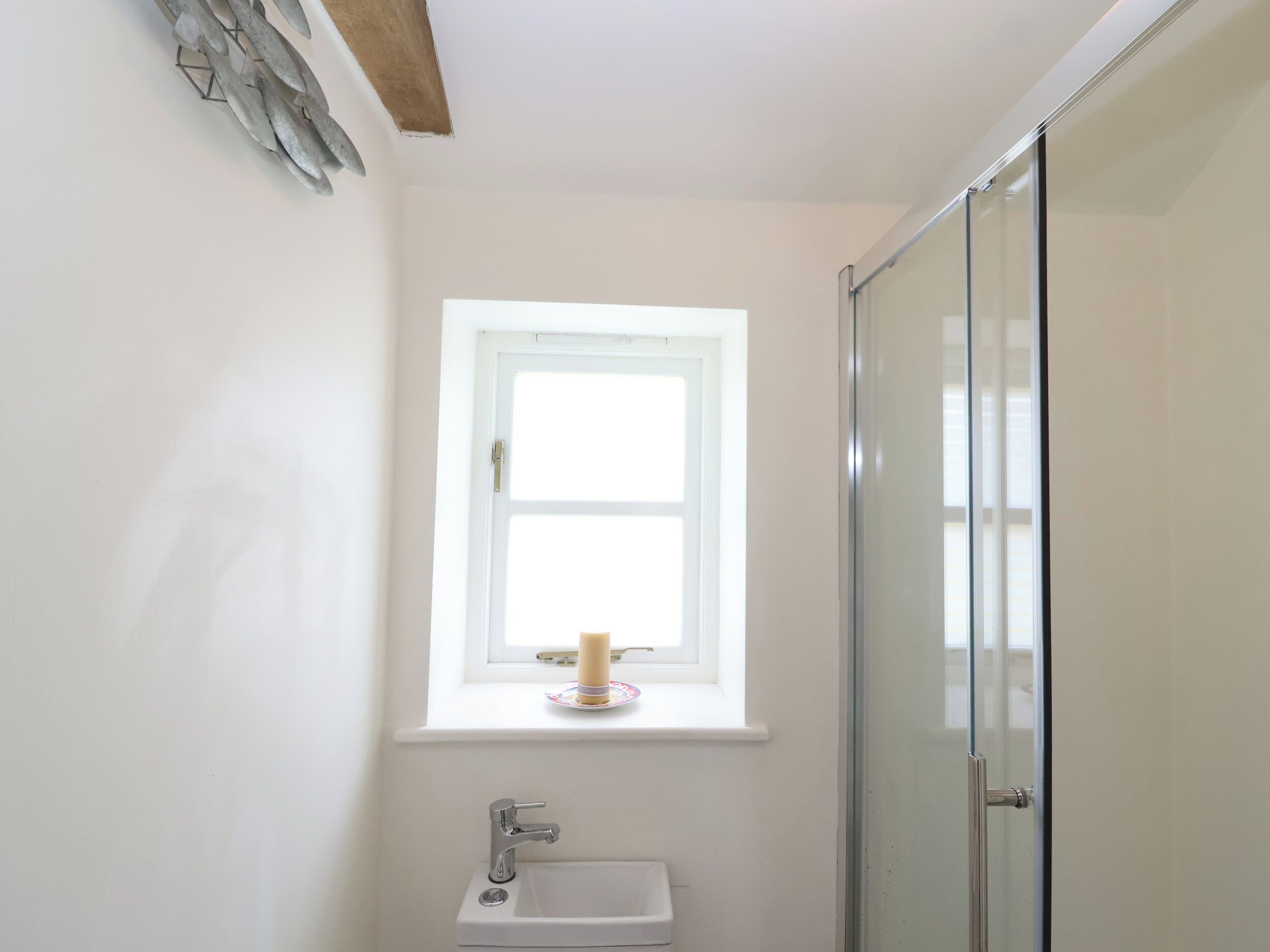 A bathroom with a window, a sink, and a shower.