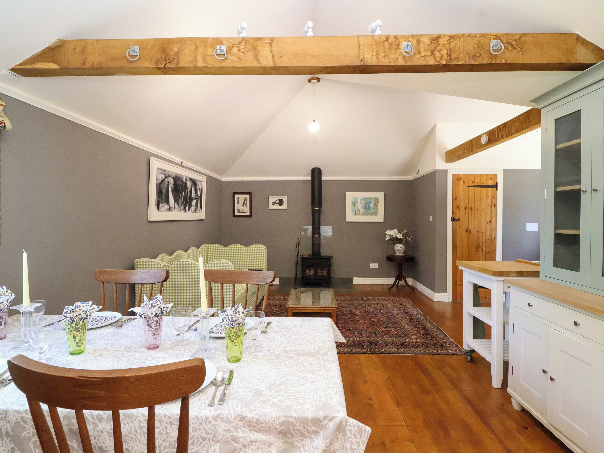 A dining area with a table set for four, a sofa, a fireplace, and a cabinet.