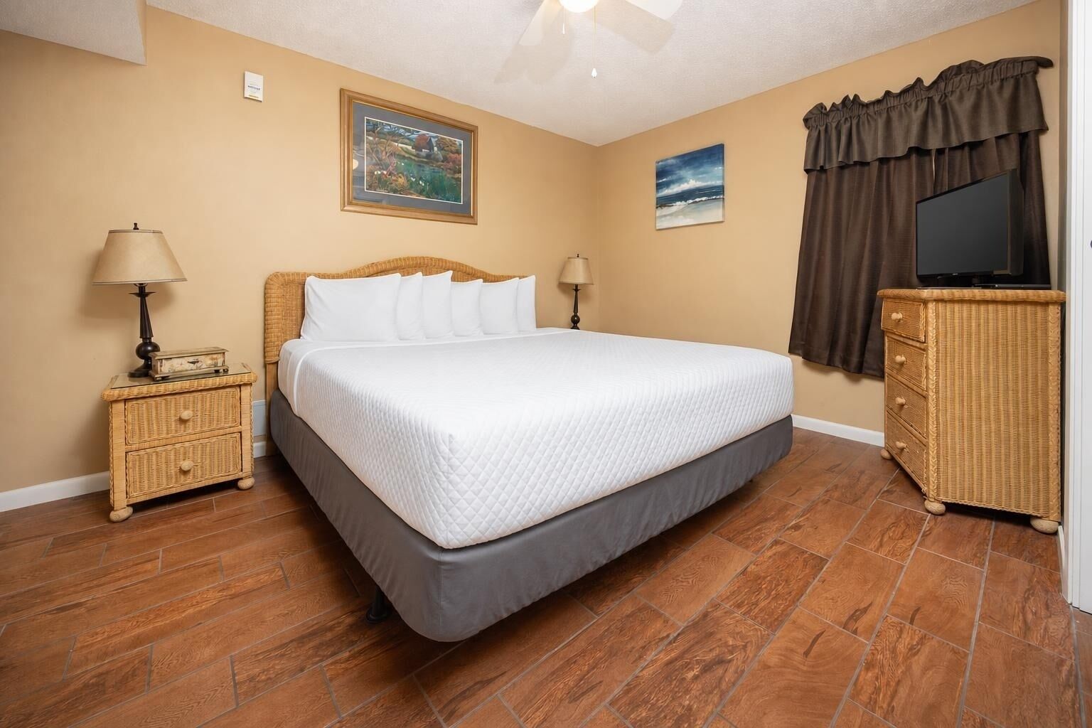 A bedroom with a bed, two nightstands, a dresser, and two wall-mounted lamps.