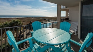 A balcony with a table and chairs, overlooking a beach and ocean. - Phoenix Vii 7214 1 Bedroom Condo (Orange Beach)