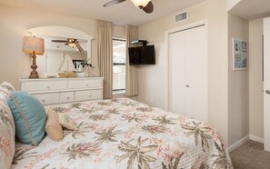 A bedroom with a bed, dresser, ceiling fan, TV, and a door. - Phoenix Vii 7214 1 Bedroom Condo (Orange Beach)
