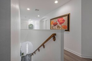 A staircase with a wooden handrail and a painting of flowers on the wall. - Wh2584 - 6BR House With Pool Near Disney Parks (Kissimmee)
