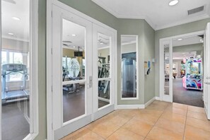 A hallway with glass doors leading to a fitness area and a children's play area. - Wh2584 - 6BR House With Pool Near Disney Parks (Kissimmee)
