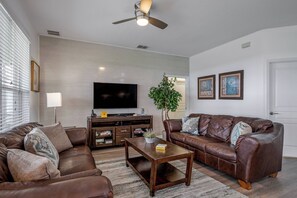 A living room with two brown leather sofas, a wooden coffee table, a flat-screen TV, and a ceiling fan. - Wh2584 - 6BR House With Pool Near Disney Parks (Kissimmee)