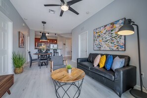 Ein modernes Wohnzimmer mit einer schwarzen Ledersofa, einem Holztisch und einem Essbereich mit einer Kronleuchter.