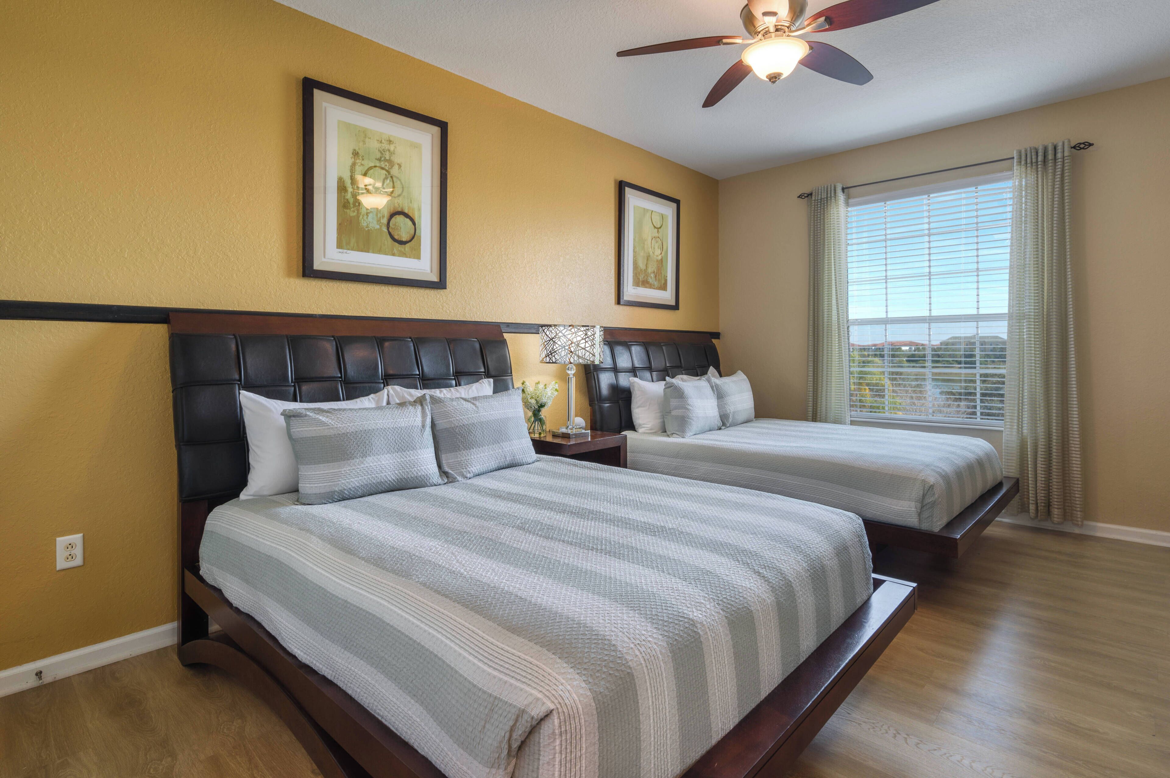 A bedroom with two beds, a ceiling fan, and a window with curtains.