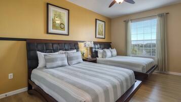 A bedroom with two beds, a ceiling fan, and a window with curtains.