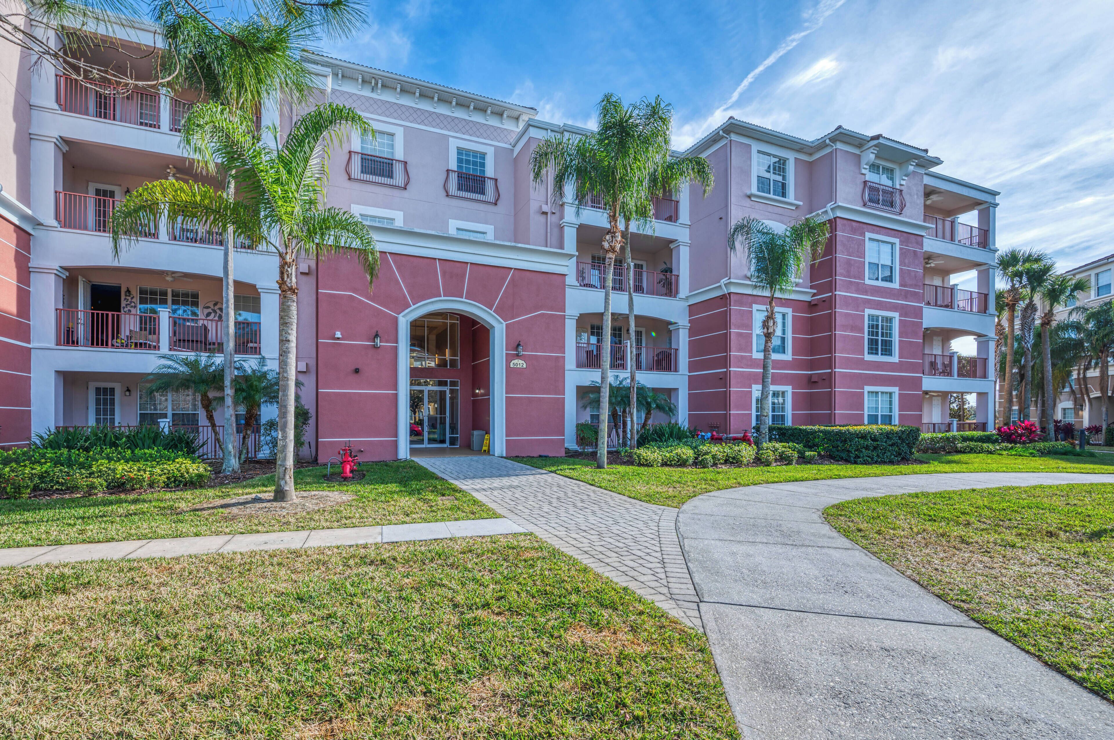 A multi-story hotel with balconies, a central entrance, and a landscaped garden.