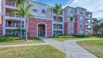 A multi-story hotel with balconies, a central entrance, and a landscaped garden.