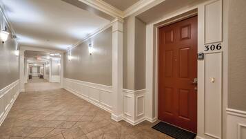 A hallway with a red door marked 306, white walls, and a tiled floor.